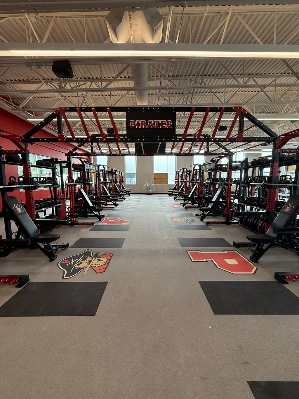 Pewaukee High School weight room with rows of red and black Pirates power racks and benches installed by AFS