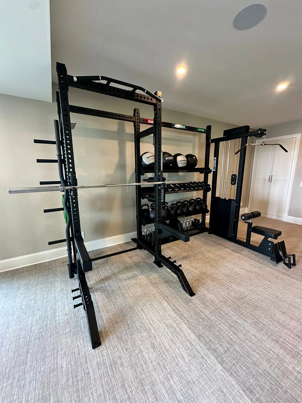 Power rack, cable column and dumbbell storage along the wall of a private strength room